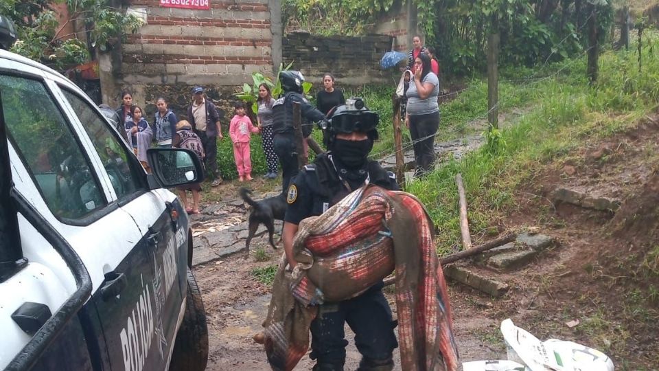 Un policía cargando el cuerpo de uno de los niños fallecidos.