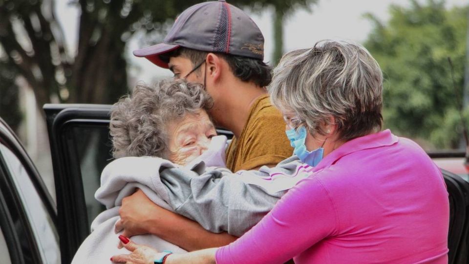 Una abuelita es abrazada por un joven tras sufrir maltrato. Foto: Especial