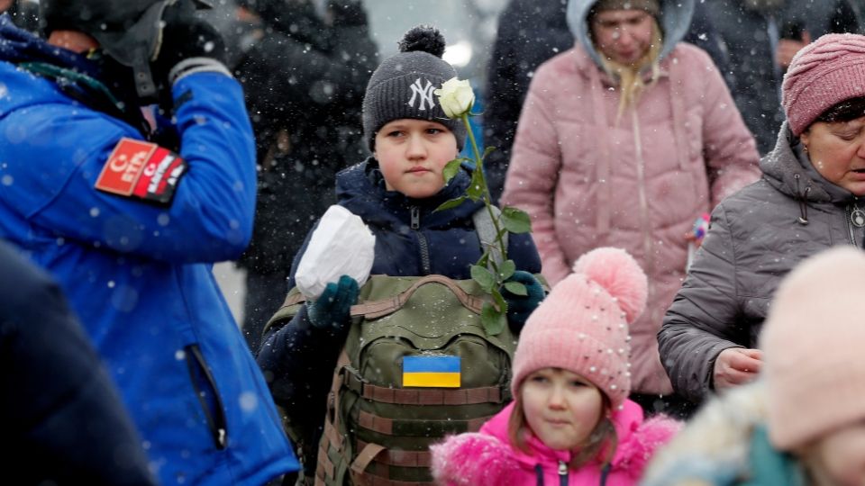 Un niño ucraniano, que lleva una mochila militar y una rosa blanca mientras camina con miembros de su familia después de pasar por el cruce fronterizo de Siret, en el norte de Rumania. Foto: EFE / EPA / Robert Ghement