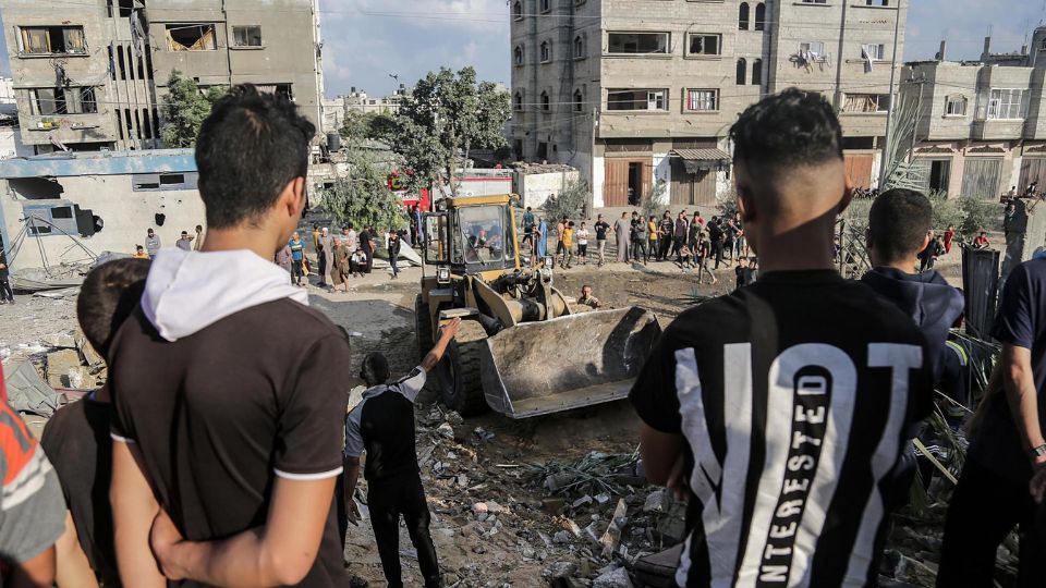 Palestinos buscan cadáveres y supervivientes entre los escombros de un edificio residencial derribado por un ataque aéreo israelí, en el campo de refugiados de Khan Younis, en el sur de la Franja de Gaza.