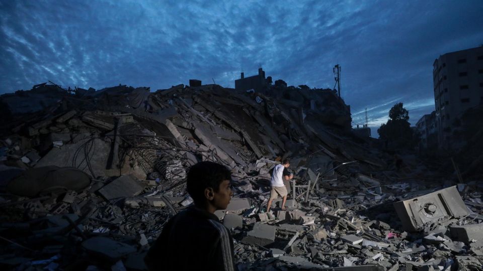 Menores inspeccionan los alrededores destruidos de la Torre Palestina después de que aviones de combate israelíes la atacaran en la ciudad de Gaza.