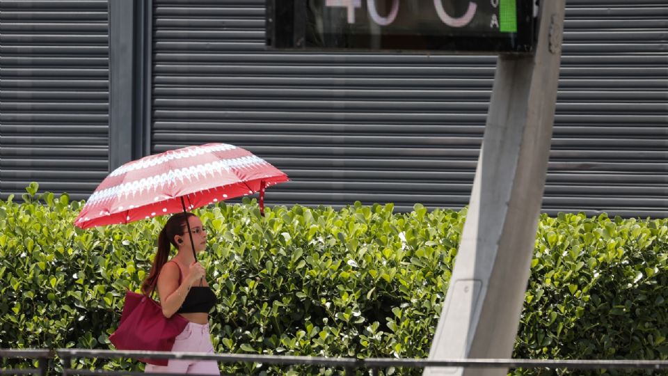 Joven se protege del sol con una sombrilla en la avenida Paulista, dónde los termómetros urbanos registran una temperatura de 40,0 grados centígrados