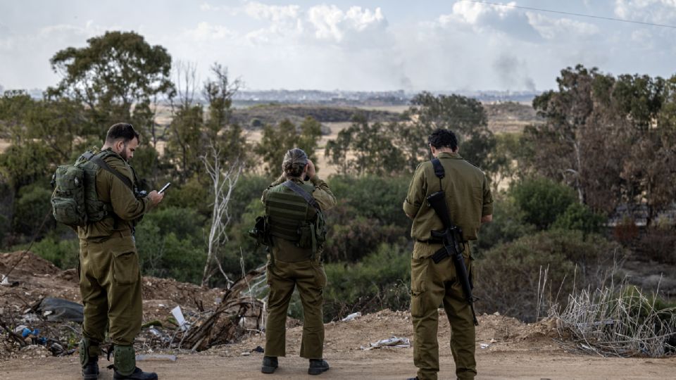 Soldados reservistas del ejército israelí observan el humo que se eleva.