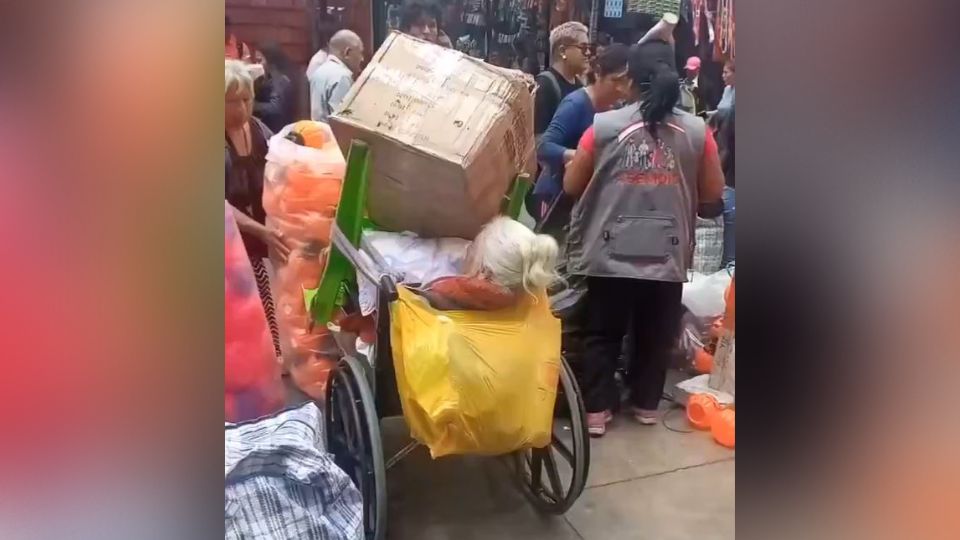 Mujer en silla de ruedas con cajas encima.