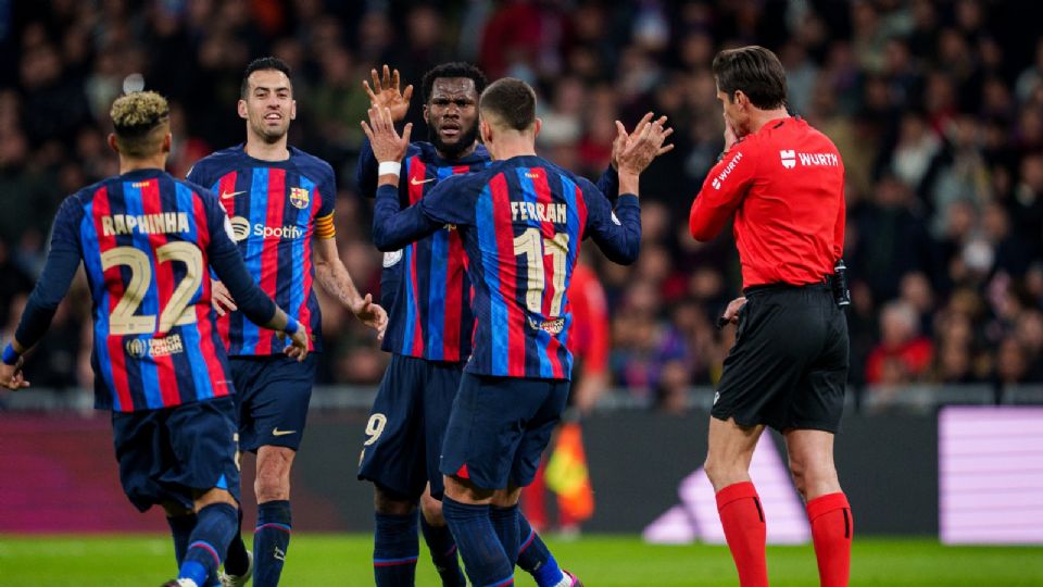 Futbolistas del FC Barcelona festejan un gol frente a un árbitro