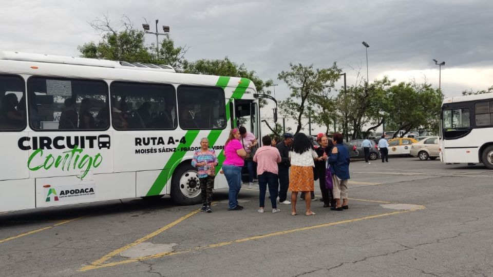 Personas arribando en camiones al Gimnasio Nuevo León.