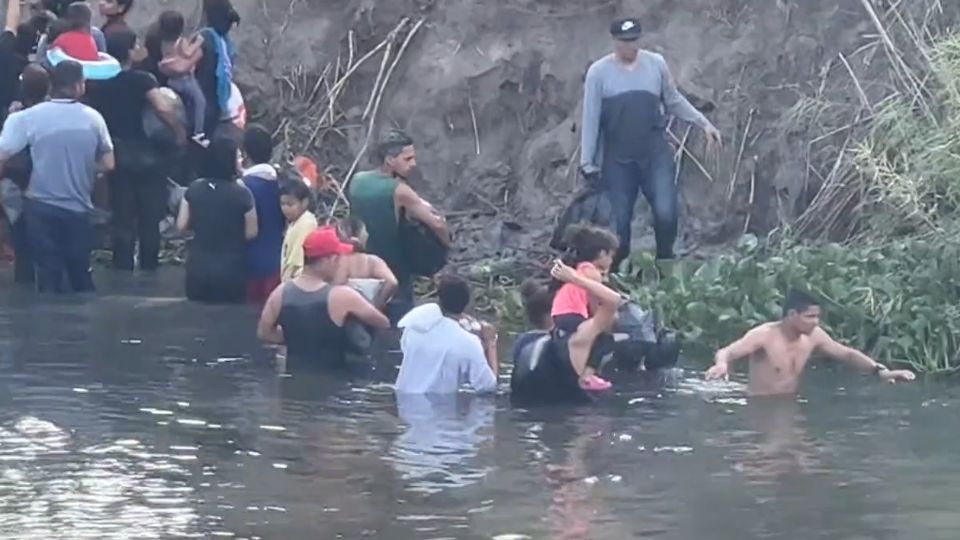 Migrantes con menores tratando de cruzar el Río Bravo.