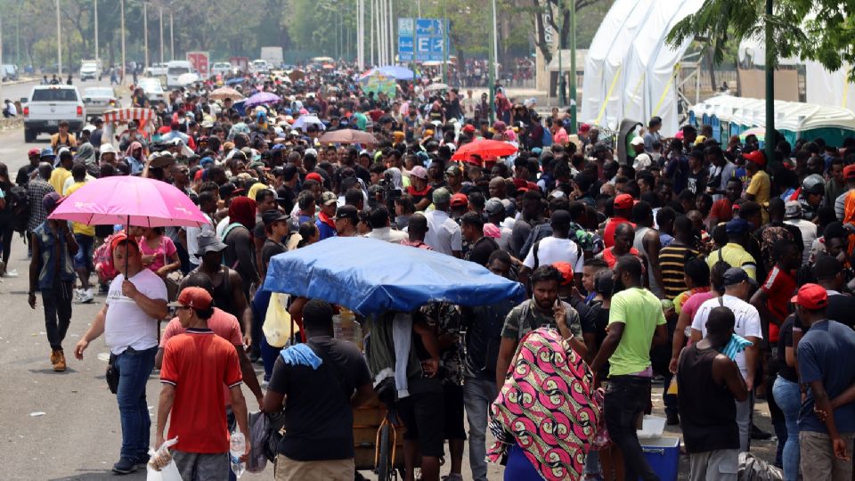 Migrantes hacen fila para tramitar papeles migratorios.