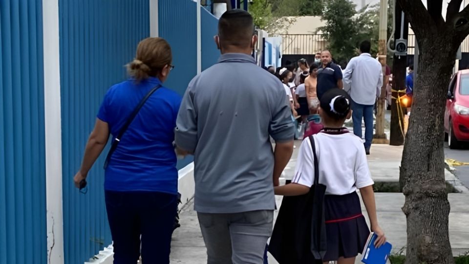 Padres de familia llevan a su hija a la escuela