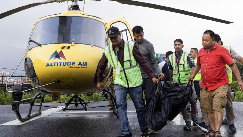 Personal y policías de las aerolíneas nepalíes llevan los cuerpos de las víctimas.