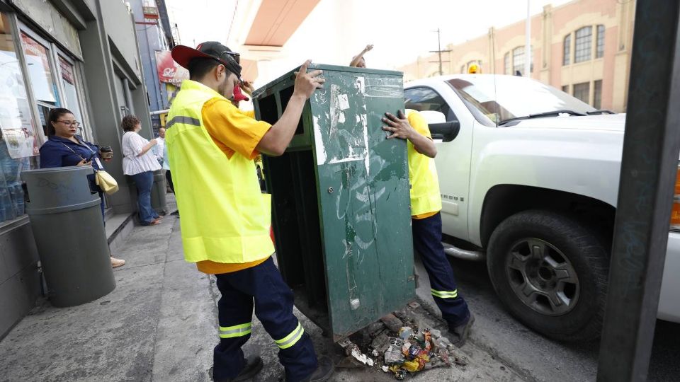 Personal con un bote de basura en el Centro de Monterrey.