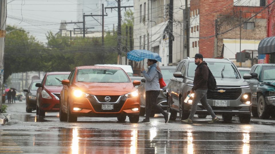 Personas caminando por el centro de Monterrey con su paragua, tras lluvia en la entidad