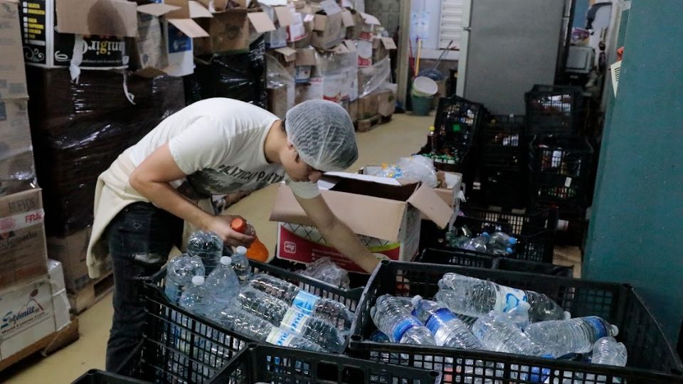 Joven acomoda cajas con botellas de agua