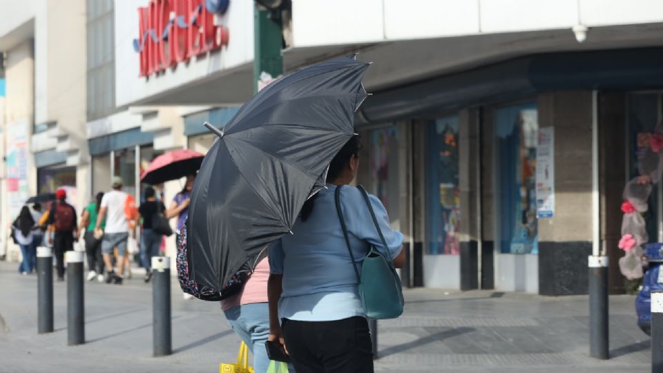 Regios caminan por calles del centro de Monterrey con su sombrilla ante las altas temperaturas