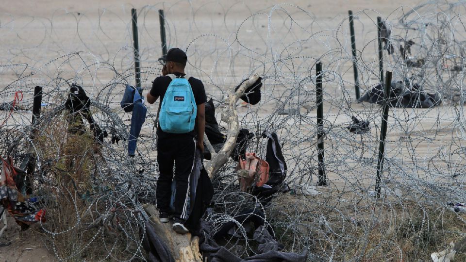 Migrantes buscan cruzar una alambrada de navajas y púas, en el área fronteriza con Estados Unidos, en Ciudad Juárez.