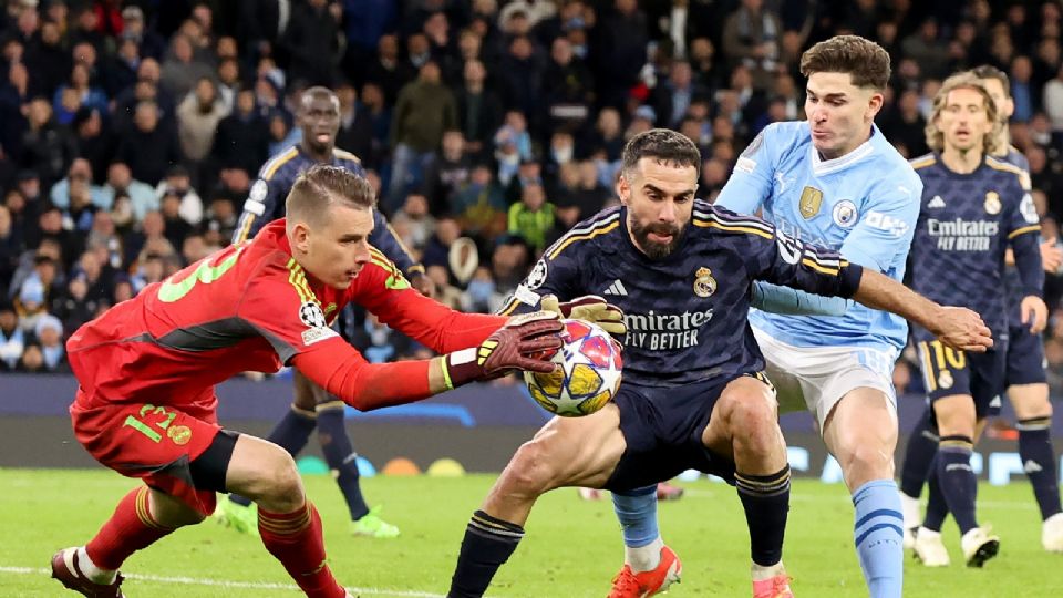 El portero del Real Madrid, Andriy Lunin (I), llega al balón antes que su compañero Dani Carvajal (C) y Julian Alvarez del Manchester City durante el partido de vuelta de cuartos de final de la UEFA Champions League.