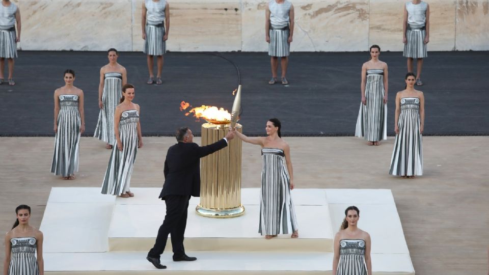 La actriz griega Mary Mina en el papel de la sacerdotisa, entrega la antorcha olímpica al presidente del Comité Olímpico Griego Spyros Kapralos, durante la ceremonia de entrega de la antorcha olímpica.