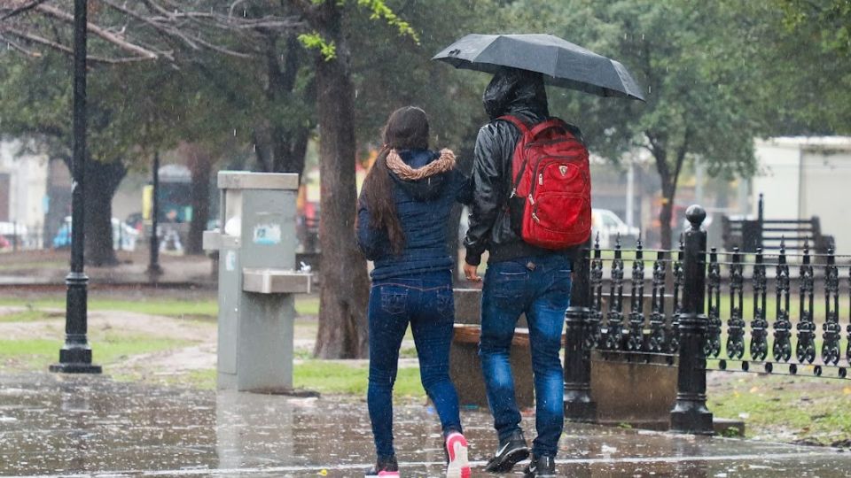 Jóvenes caminan entre la lluvia en Monterrey