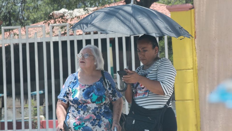 Mujeres bajo sombrilla durante jornada calurosa