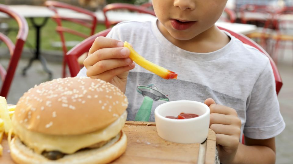 Niño come papa frita con cátsup