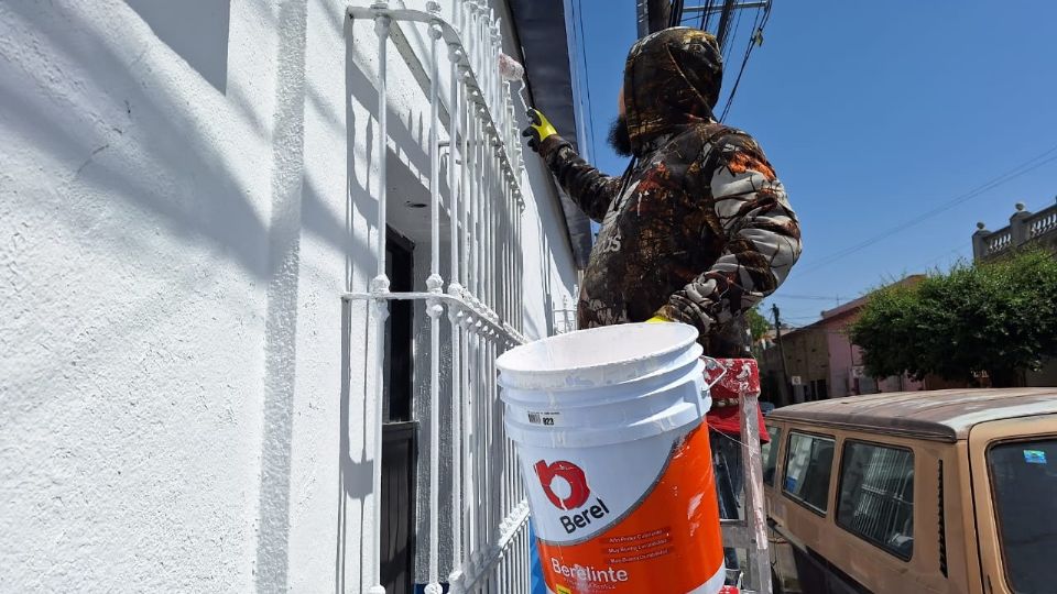 Hombre pintando pared pese a altas temperaturas.