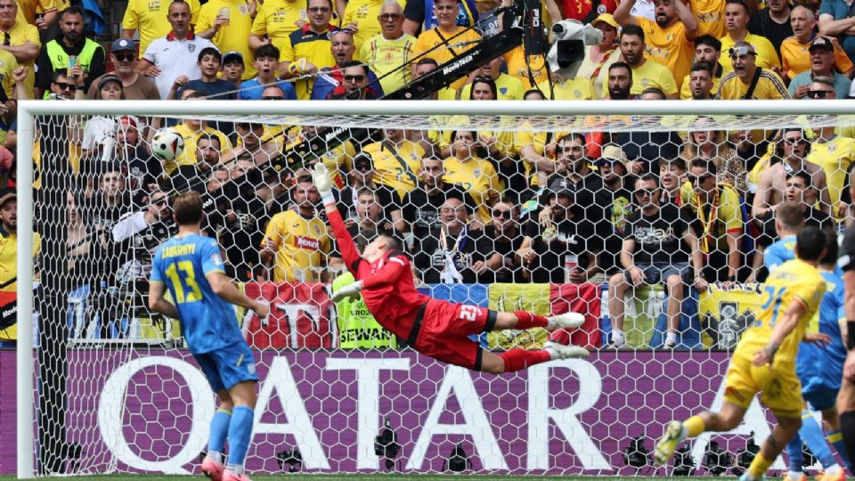 Nicolae Stanciu de Rumania (D) anota el gol 1-0 contra el portero Andriy Lunin (C) de Ucrania durante el partido de fútbol del Grupo E de la EURO 2024 entre Rumania y Ucrania.