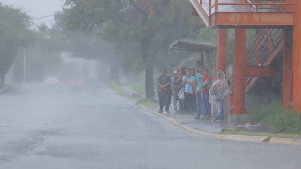 Personas aguardan por un camión en pleno aguacero