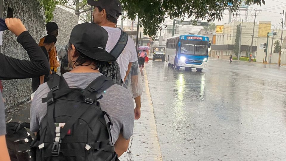 Usuarios esperan camiones bajo la lluvia