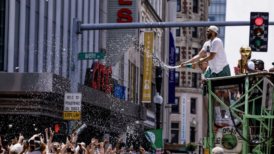 El alero de los Boston Celtics, Jayson Tatum, les echa agua a los aficionados mientras participa en el desfile del campeonato de la NBA del equipo en Boston, Massachusetts.