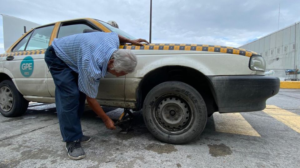 Taxista cambia la llanta de su auto tras caer en un bache