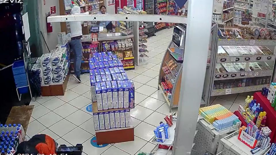 Asaltante apuntando a cajera de la farmacia.