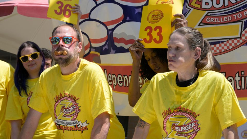 Dan 'Killer' Kennedy (i) y Molly Schuyler devoran hamburguesas durante la 15 edición del concurso anual de comer hamburguesas | EFE/ Lenin Nolly