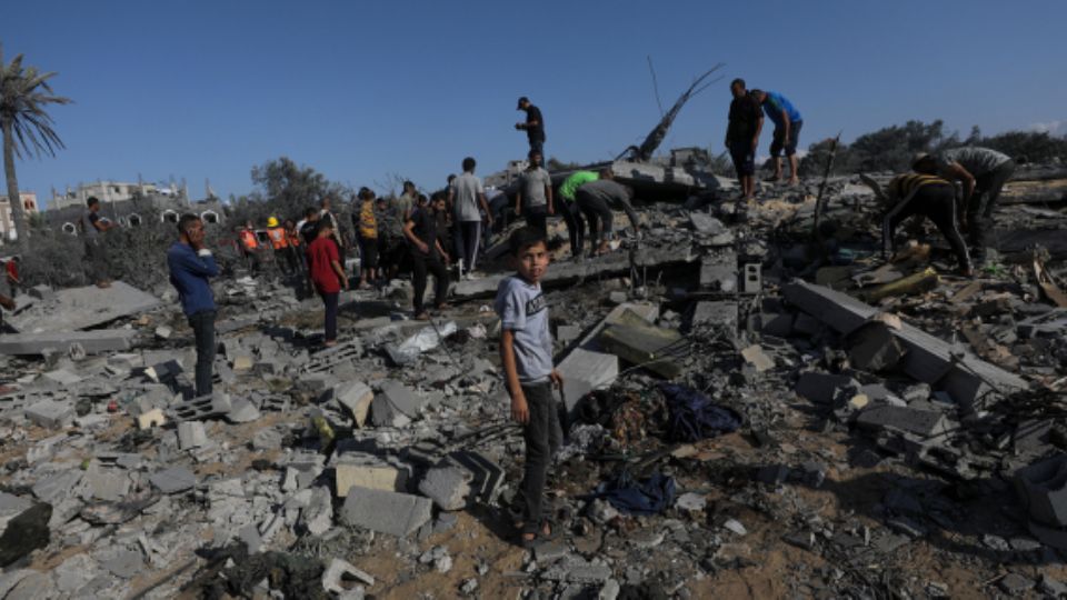 Palestinos buscan entre los escombros de una casa destruida tras los ataques aéreos israelíes en el campo de refugiados de Al-Maghazi, Franja de Gaza, 17 de octubre de 2024.