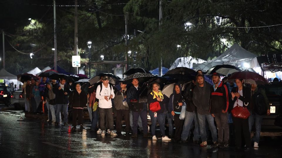 Personas esperando el camión bajo la lluvia