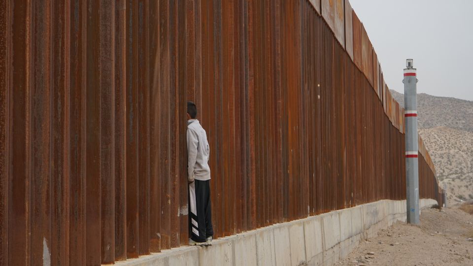 Niño migrante en el muro fronterizo