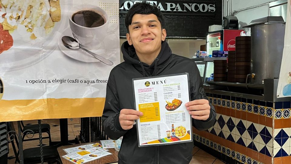 Mesero en un restaurante de Monterrey busca atraer cliente pese a las bajas temperaturas.