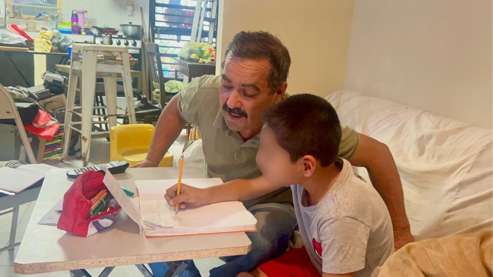 Niño autista hace su tarea con apoyo de su padre