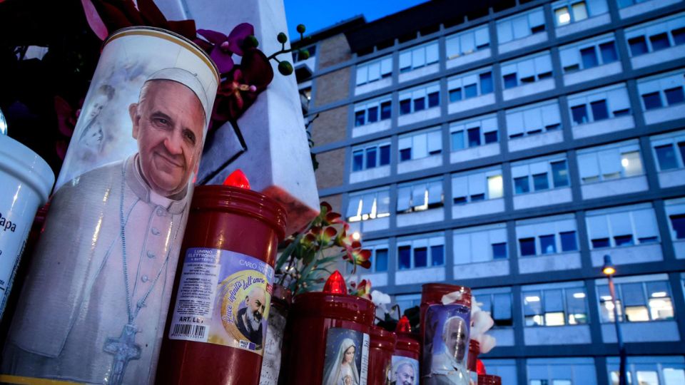 Una vela con la imagen del Papa Francisco, al pie de la estatua de San Juan Pablo II en las afueras del Hospital Universitario Gemelli, en Roma | EFE/GIUSEPPE LAMI