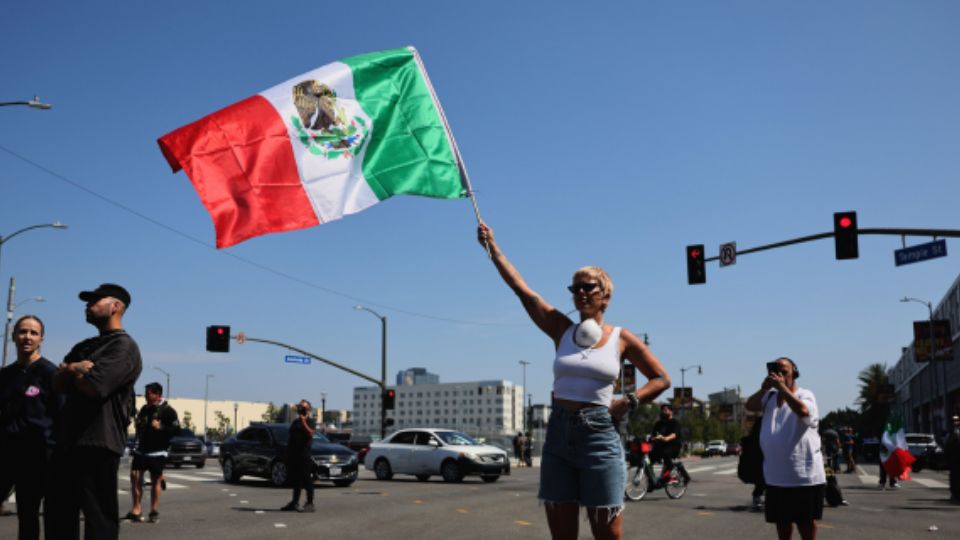 Mujer ondeando una bandera de México en protesta de Los Ángeles. 
