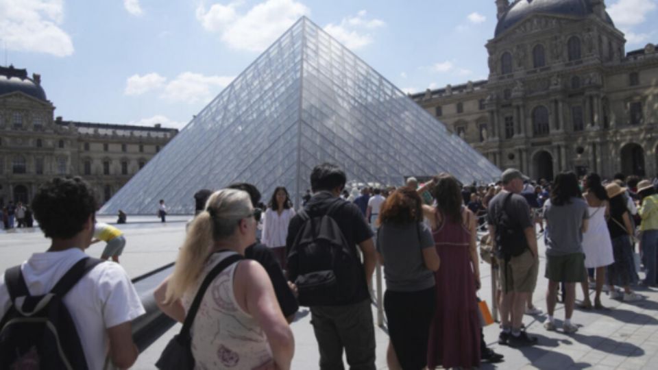Visitantes hacen fila afuera del museo de Louvre.